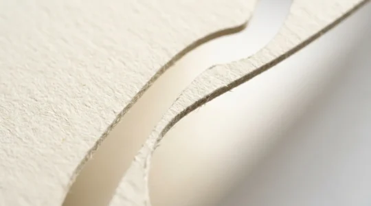 Vue macro d'une découpe précise sur papier épais révélant des détails complexes et des formes originales